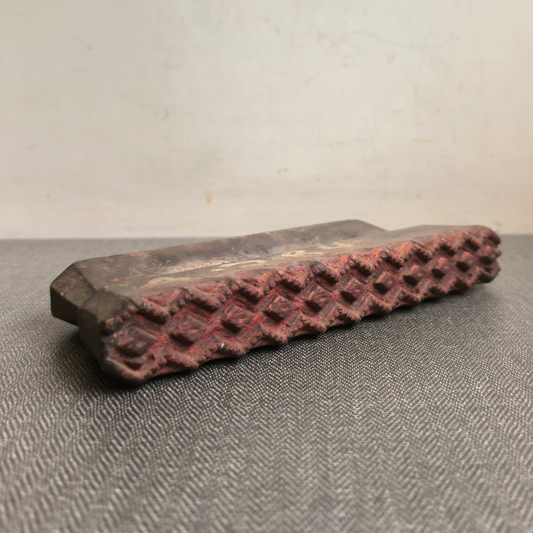 Detailed angled view of a hand-carved antique wooden printing block, showing its geometric texture.