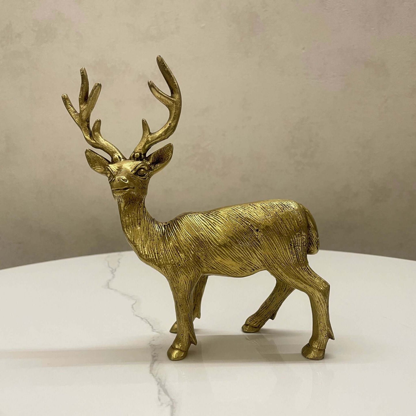 Front view of a regal standing brass deer statue with large antlers, finished in antique gold