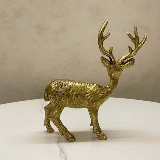 Side profile of a textured antique brass deer figurine displayed on a white marble surface