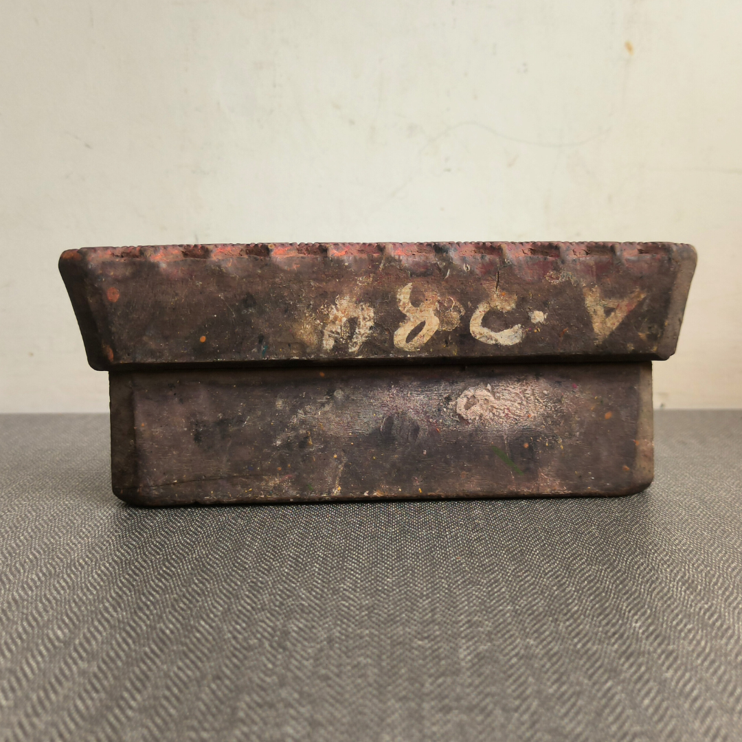 The aged handle of an antique Indian printing block, showing its dark wood patina and original markings.