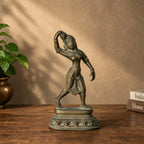 Antique brass dancing apsara statue on a wooden table beside a brass vase
