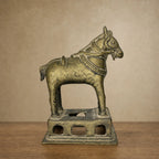 Antique brass horse statue on a pierced base, front view on a wooden table