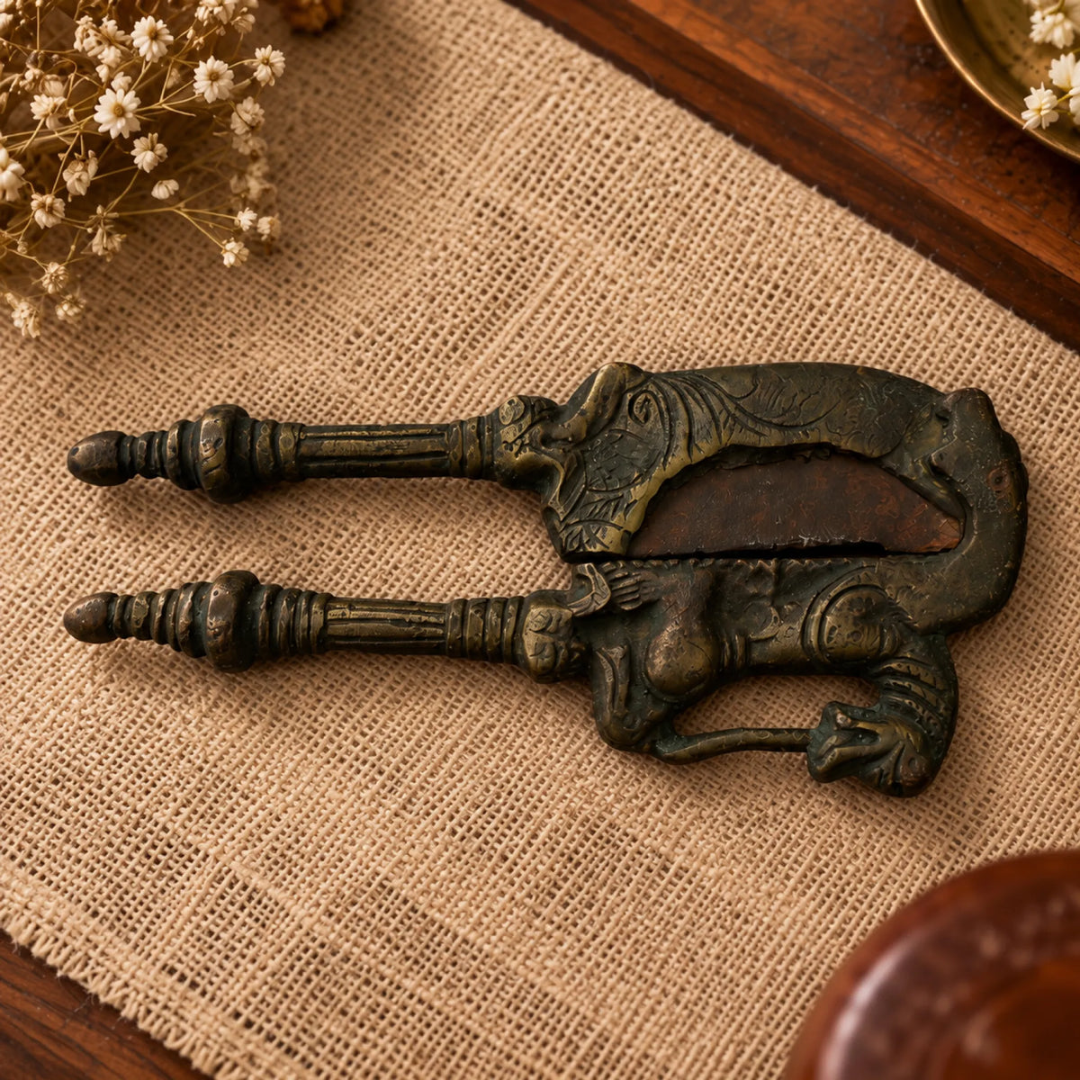 Antique nutcracker with mythical horse-and-rider figure cast at the hinge, front view on a textured surface

