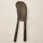 Antique nutcracker with rounded looped top with hand-engraved chevron border detail along the blade edges, front view on a textured surface
