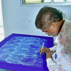 Artist hand-drawing fine ink line details on black paper using a brush
