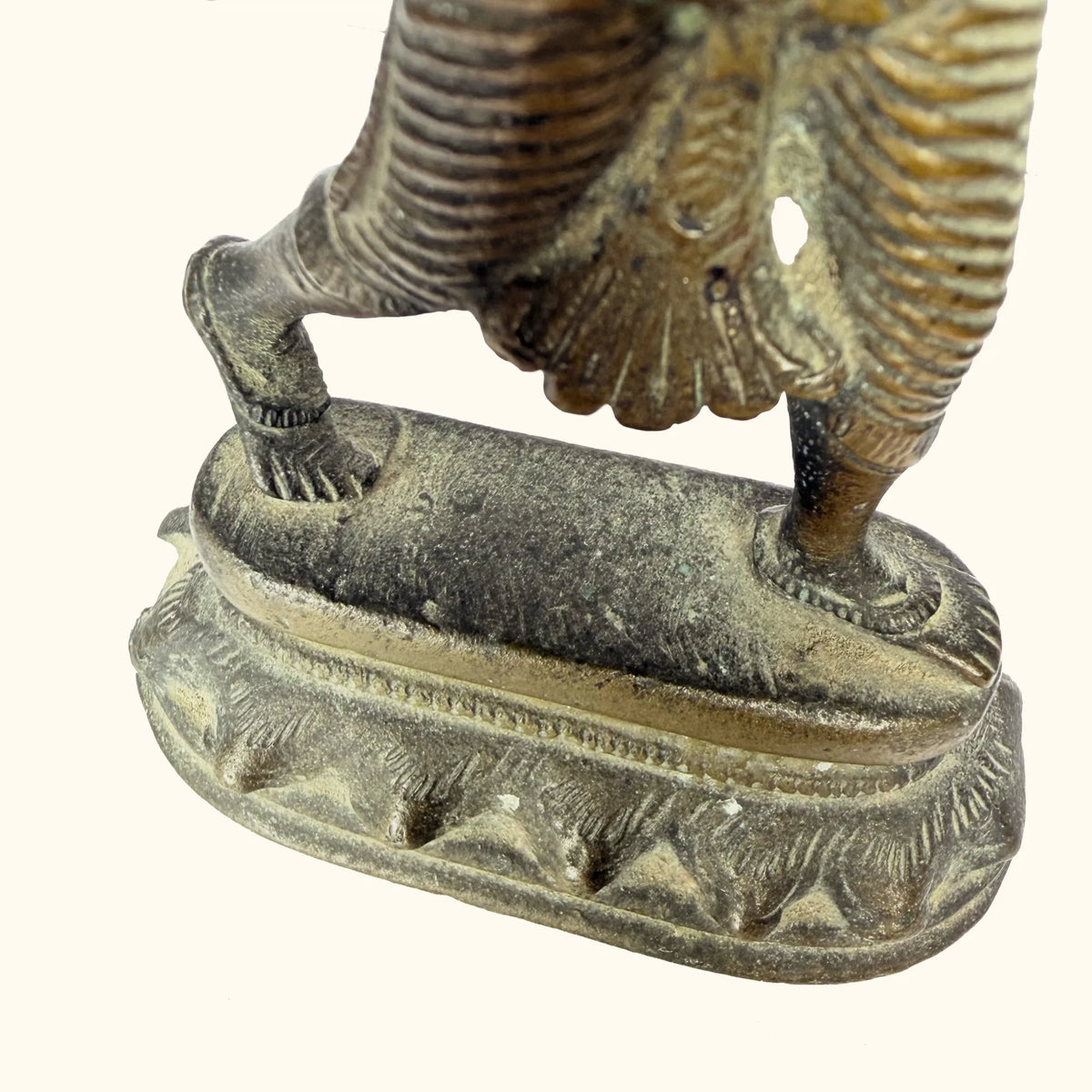 Base detail of the antique brass apsara statue on its lotus-petal pedestal
