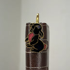 Brass rabbit bookmark with black enamel and pink accents on leather journal spine