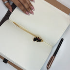 Brass rabbit bookmark with black enamel marking pages in an open notebook

