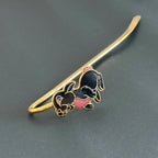 Handmade brass rabbit bookmark with black enamel and pink accents on black background