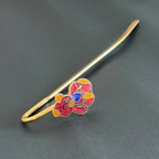 Handmade brass teddy bear bookmark with red enamel and blue heart on black background