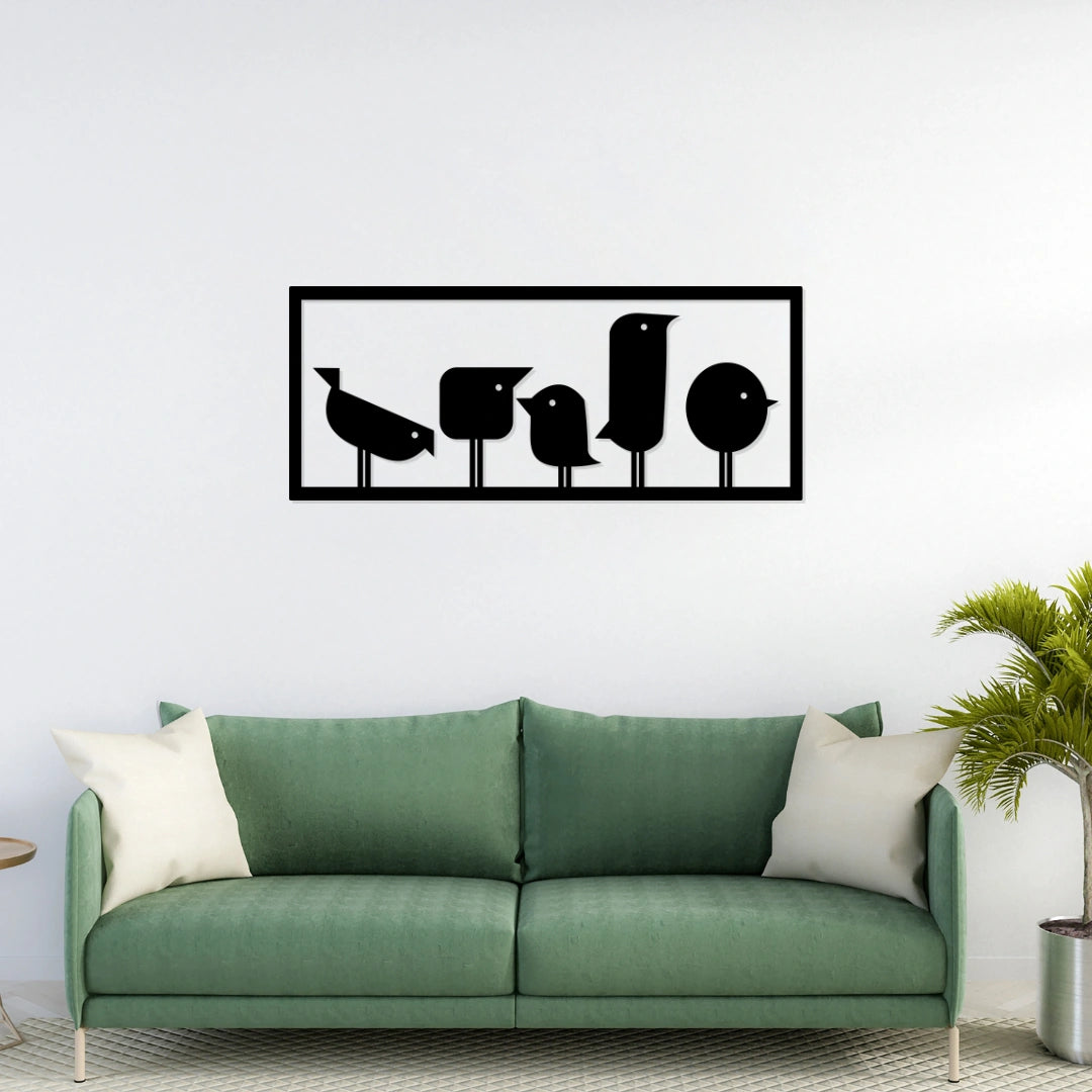 Matte black metal bird wall art in rectangular frame displayed above sofa