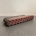Detailed angled view of a hand-carved antique wooden printing block, showing its geometric texture.