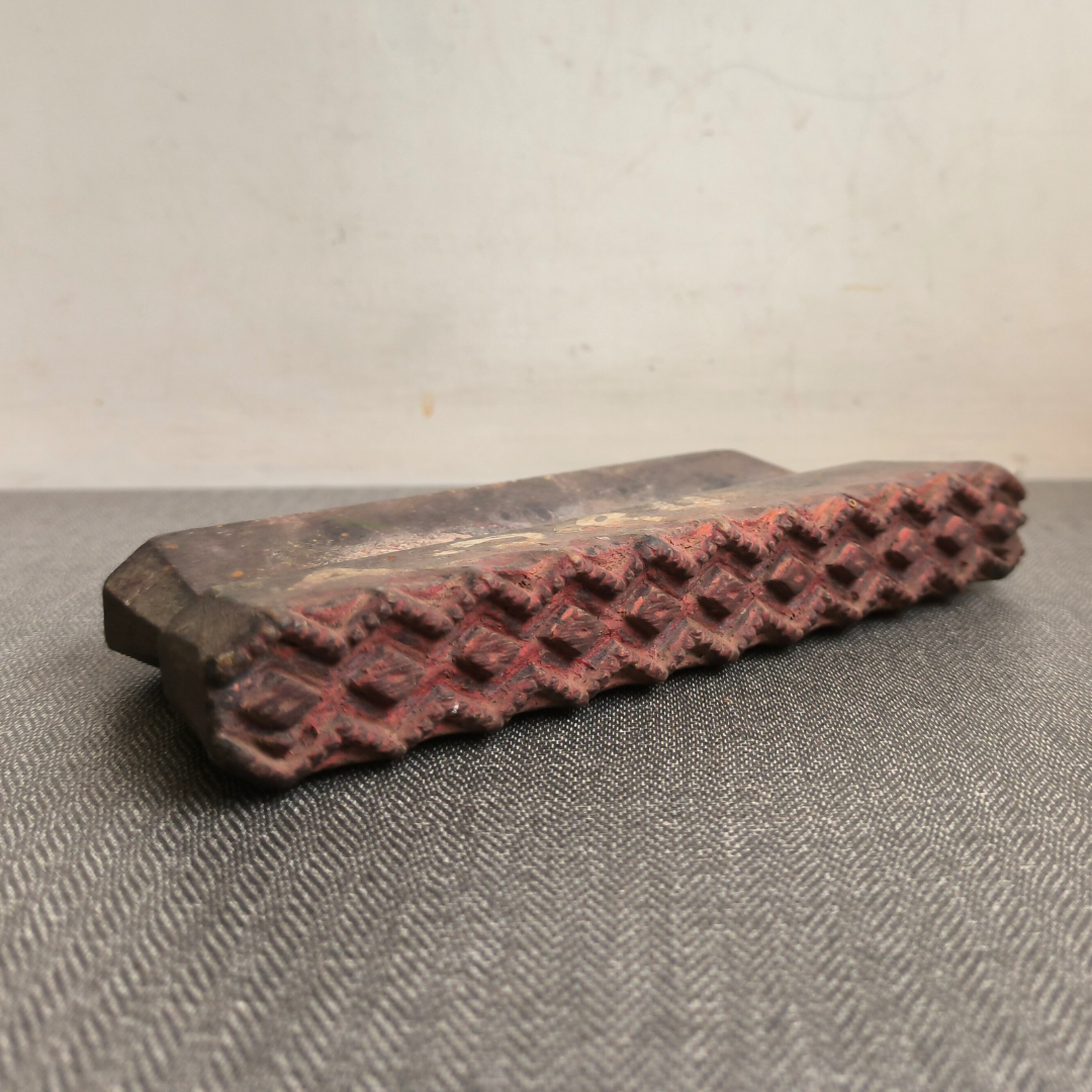 Detailed angled view of a hand-carved antique wooden printing block, showing its geometric texture.