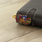 Red enamel floral brass bookmark clipped on brown leather notebook