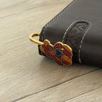 Red enamel teddy bear brass bookmark with blue heart clipped on brown leather notebook