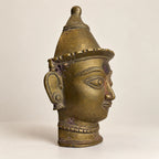 Side profile of the antique brass Gauri mask showing crown and earring detail
