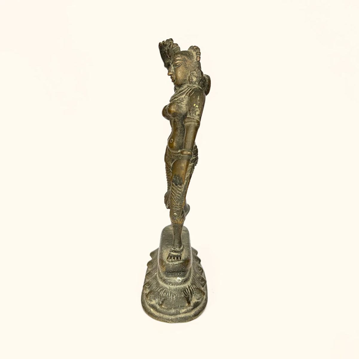Side profile of the antique brass apsara statue showing the dance posture
