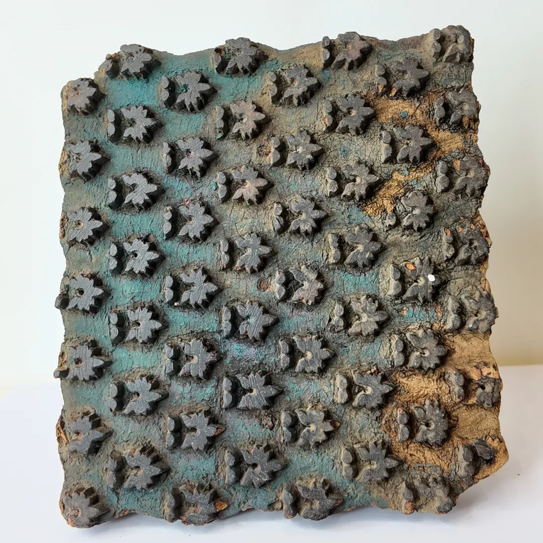 Vintage hand-carved wooden printing block with teal star bud grid design
