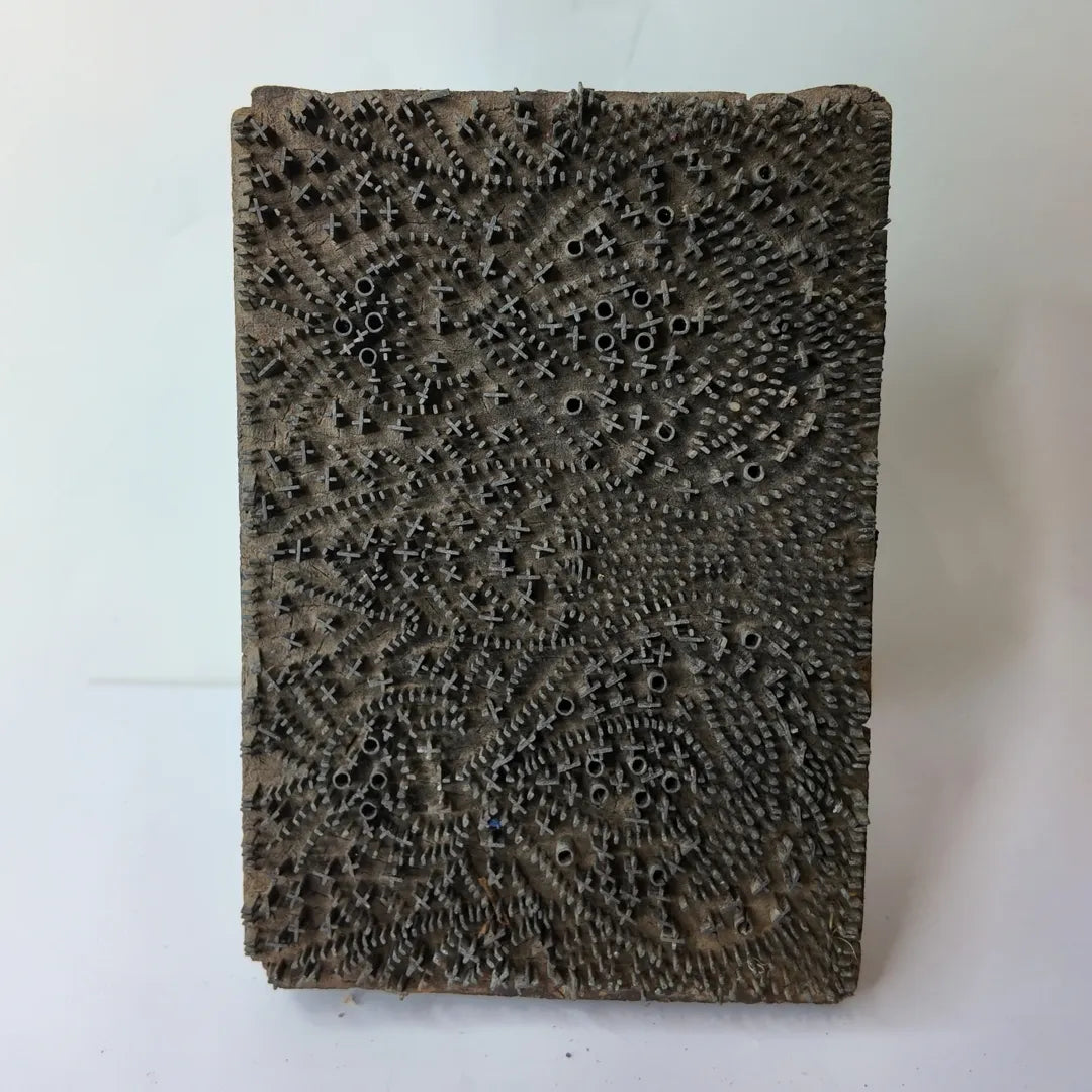 vintage Indian brass-pin wooden printing block showcasing a dense, interlocking texture of metal cross pins and hollow brass rings forming a paisley pattern