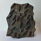 vintage Indian hand-carved wooden printing block showcasing rows of repeating raised almond shaped dashes arranged in a staggered pattern over a dark green stained background patina