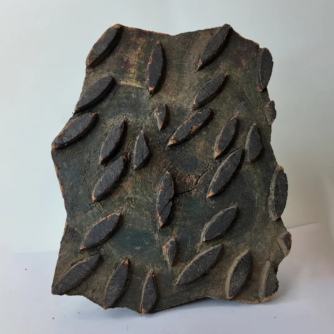 vintage Indian hand-carved wooden printing block showcasing rows of repeating raised almond shaped dashes arranged in a staggered pattern over a dark green stained background patina